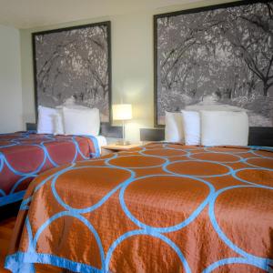 a hotel room with two beds with orange and blue at Super 8 by Wyndham Hardeeville - Savannah North in Hardeeville +46 photos