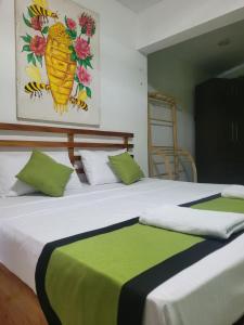 2 camas con sábanas verdes y blancas en una habitación en Beehive mountain resident, en Kandy 14 fotos más