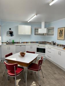 DruryExecutive Short Term Rental Drury South Auckland的配有白色橱柜、桌子和椅子的厨房