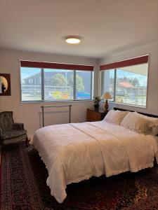 DruryExecutive Short Term Rental Drury South Auckland的一间带一张大床和两扇窗户的卧室