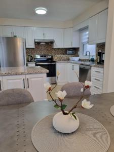 a kitchen with a table with a vase with flowers in it at Newly Renovated 3BR Upper Unit - Bright & Quiet in Richmond Hill