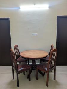 a wooden table and four chairs in a room at Sri Abirami Homestays in Tiruvannāmalai