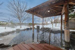 a wooden deck with a hot tub in a snow covered field at KAMENOI HOTEL Aomori Makado in Noheji