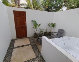 un bagno con vasca, sedie e una porta di The Cat And The Kraken Paliton Jacuzzi Suites with Solar and Starlink a Siquijor Altre 10 foto