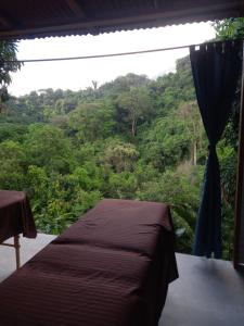 a bed in a room with a view of a forest at Tukamping Private Mountain Retreat Minca in Minca