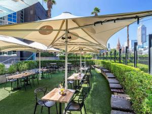 un restaurante con mesas y sillas bajo una sombrilla grande en Quay West Suites Melbourne, en Melbourne