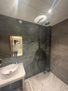 TuljapurThe Skyland Hotel And Restaurant的画画带水槽的浴室的人