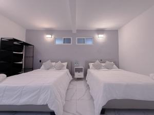 カンクンにあるDowntown Suites - Hotel Boutique by Marafの白い壁の部屋にベッドが2つある