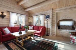 een woonkamer met een rode bank en een tafel bij Timber Cabin With Panoramic Views At Spåtind in Etnedal