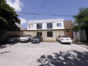 カンクンにあるDowntown Suites - Hotel Boutique by Marafの車道に3台の車が駐車されている家