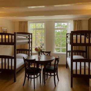 a room with bunk beds and a table and chairs at Hotel Prinsenhof Amsterdam in Amsterdam