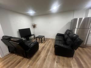 sala de estar con 2 sillas de cuero y nevera en Private room in Basement suite, en Edmonton