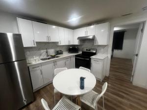 a kitchen with white cabinets and a white table and chairs at Private room in Basement suite in Edmonton