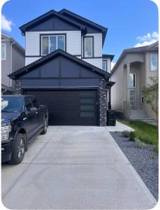 un coche aparcado frente a un garaje negro en Private room in Basement suite, en Edmonton