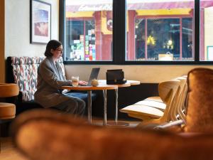 a woman sitting at a table with a laptop at Hotel Maison Louise Lille Centre - Handwritten Collection in Lille