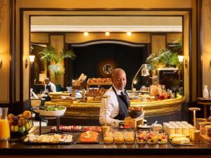 a man sitting in front of a buffet of food at l'Echiquier Opéra Hotel Paris - MGallery Collection in Paris