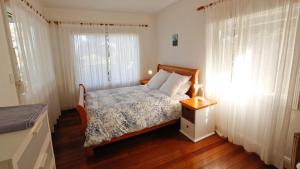 una camera da letto con un letto, pavimenti in legno e finestre di Lakehouse Akolele 19 Flower Circuit- Wallaga Lake Bermagui a Central Tilba