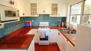 una cucina con mobili bianchi e un forno a piano cottura di Lakehouse Akolele 19 Flower Circuit- Wallaga Lake Bermagui a Central Tilba