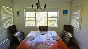 una sala da pranzo con tavolo in legno e finestra di Lakehouse Akolele 19 Flower Circuit- Wallaga Lake Bermagui a Central Tilba Altre 2 foto