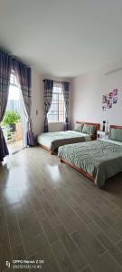 a bedroom with two beds and a large window at Thuy's homestay in Vung Tau