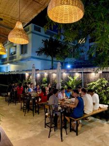 シェムリアップにあるGecko Hostelのレストランのテーブルに座っている人々のグループ