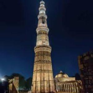 una torre del reloj alta en una ciudad por la noche en The Hosteller Delhi, International Airport, en Nueva Delhi