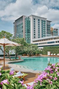 a hotel swimming pool with a large building in the background at Grand Hyatt Erawan Bangkok in Bangkok