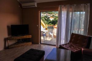 uma sala de estar com televisão e vista para uma varanda em Apartman Selena em Trebinje
