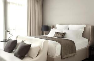 a white bedroom with a large bed and a couch at Rongratana Executive Residence Bangkok in Bangkok
