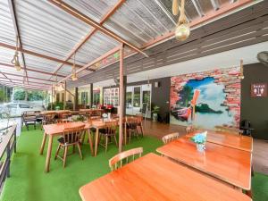 a restaurant with wooden tables and chairs and a brick wall at Royal Hill Satun Hotel in Ban Pak Ba Ra