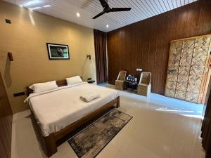 a bedroom with a bed and two chairs in it at Kaziranga Tea Nest Homestay in Kāziranga