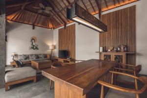 a living room with a wooden table and a couch at Teratai Villa Canggu by Ini Vie Hospitality in Canggu