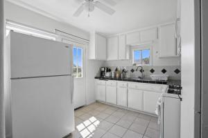 a kitchen with white cabinets and a white refrigerator at Charming House Free RV Parking in Upland +7 photos