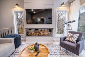 a living room with a fireplace with a tv at Ski in - Ski out - SPA & Pool Table - Le Konect in Saint-Philémon