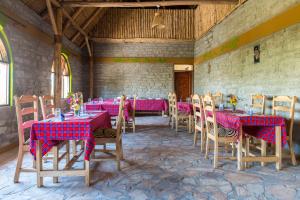 a dining room with tables and chairs with pink tablecloths at Kyaninga Royal Cottage in Fort Portal