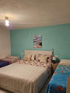 Un dormitorio con una cama y una pared azul. en Paraiso S, en Villasimius