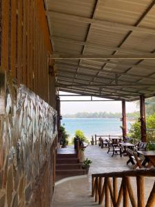 a patio with tables and benches and the water at Tadangbay bungalow in Koh Chang Ranong