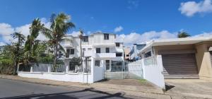 una casa blanca con una valla y palmeras en Villa Accacia, en Trou aux Biches