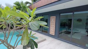 a house with a palm tree next to a pool at Sarang Jati Mansion in Ban Saiyuan (1)