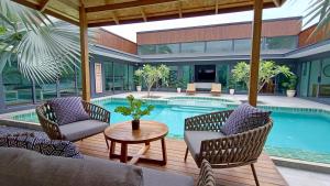 a patio with a pool and chairs and a table at Sarang Jati Mansion in Ban Saiyuan (1)