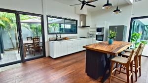 a kitchen with white cabinets and a wooden table at Sarang Jati Mansion in Ban Saiyuan (1)