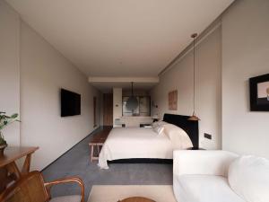 a bedroom with a white bed and a couch at Shanyu Art Garden Homestay in Fuzhou