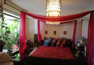 Un dormitorio con una cama con dosel y cortinas rojas. en Baan Pim, en Chiang Mai