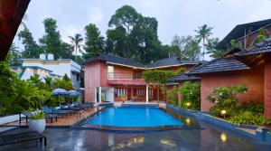 a swimming pool in front of a house at Deshadan Cliff & Beach Resort,Varkala in Varkala