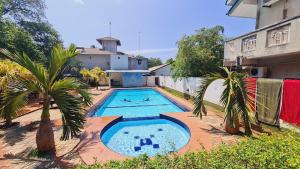 a large swimming pool with palm trees in front of a building at Yala Visit Villa in Tissamaharama