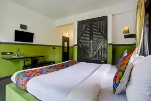 1 dormitorio con 1 cama blanca grande y paredes verdes en FabHotel DDHYANA The Wellness Centre and Resort, en Panaji