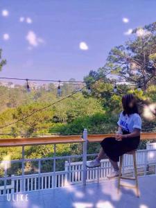 una donna seduta su una sedia su un balcone che guarda il panorama di Villa mini 3 phòng ngủ Đà Lạt a Xuan An