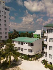 a building with a green roof next to tall buildings at Dhiffushi Inn in Dhiffushi +48 photos