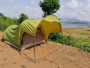班达尔达拉Bhandardara I land Camping的一顶绿褐色相间的帐篷静静地躺在泥土里。