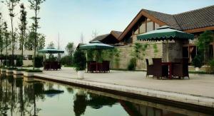 a building with tables and umbrellas next to a body of water at Xinjin Celebrity City Hotel in Xinjin